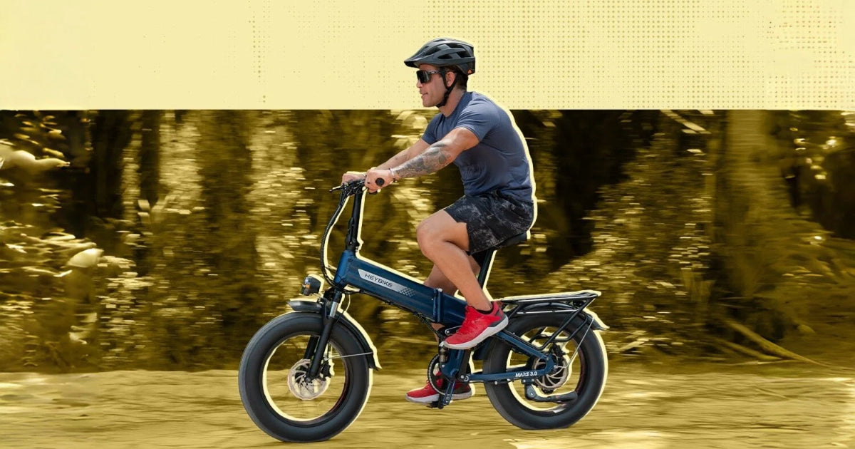 Male rider with black helmet riding dark blue foldable fat tire ebike on sunlit woodland dirt trail