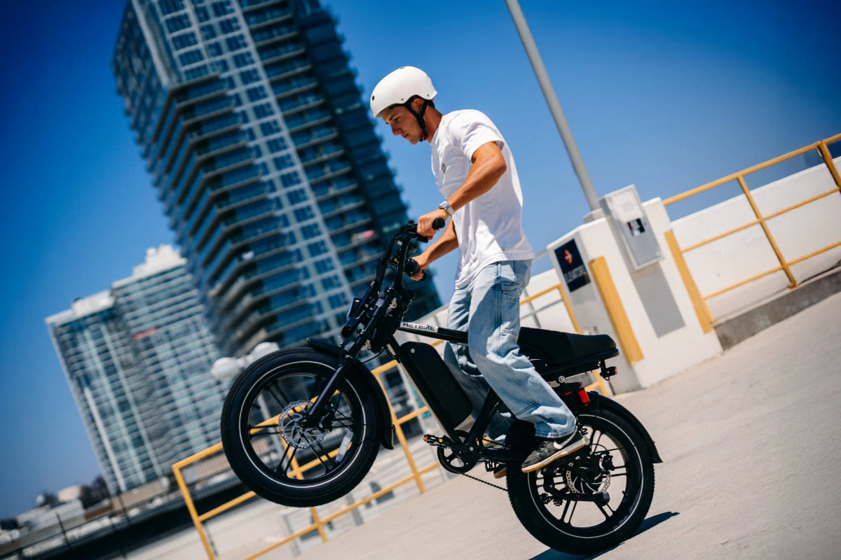 Rider performing a wheelie on a black Heybike Titan moped-style electric bike in the city