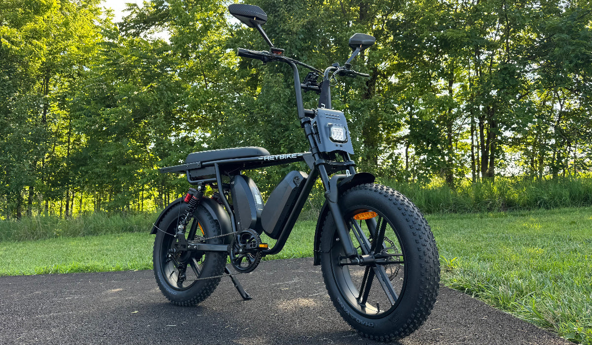 Black Heybike Saturn moped-style eBike parked on a tree-lined path