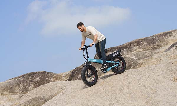 A man is riding a Mars 2.0 folding fat tire e-bike downhill apace