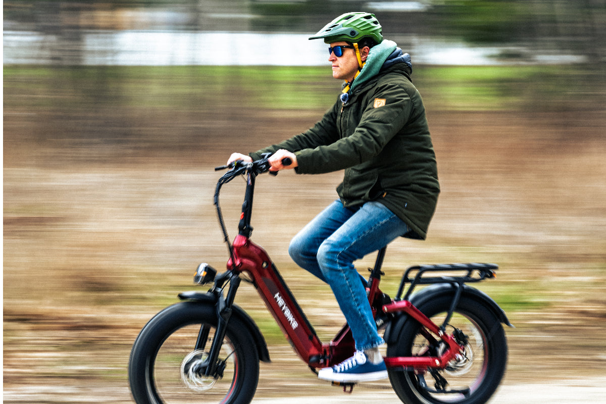 Helmeted rider riding a red Heybike electric bike on a paved path.