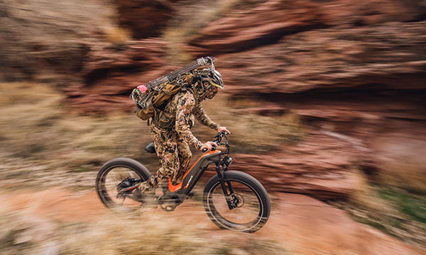A man is riding a Hero e-bike to hunt wild animals