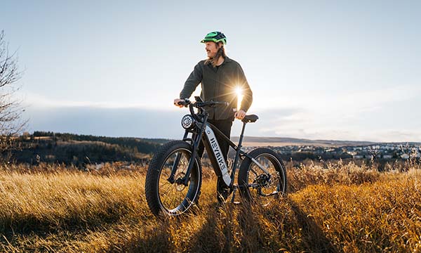 A man is holding his electric bike outside