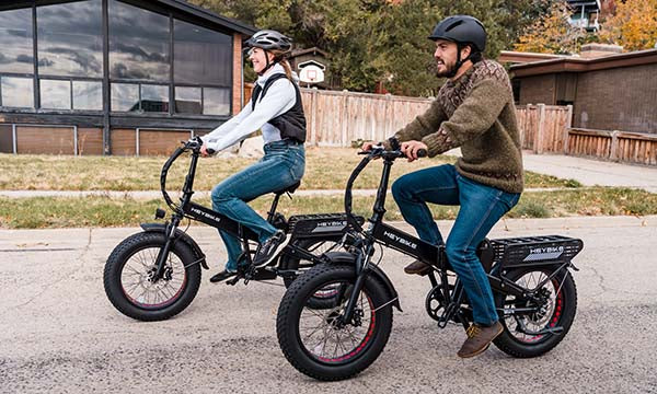 A man holds a brown e-bike outdoors